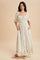 woman wearing a cream floral maxi dress with puff sleeves and pockets, standing against a beige background