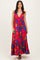 woman wearing a vibrant pink maxi dress with colorful floral patterns and a deep v-neckline