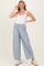 woman wearing a white tank top and light blue striped maternity pants with an elastic waistband and sneakers