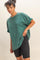 woman wearing a green oversized crew neck t-shirt with rolled sleeves and black bike shorts