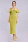 woman wearing a light green off-shoulder ribbed midi dress with ruffle details and a tie at the neckline