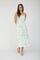 woman wearing a white maxi dress with green floral print and thin straps