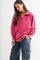 woman wearing a pink long sleeve polo-style shirt with a loose fit and high collar paired with dark cargo pants