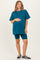 woman wearing a teal maternity t-shirt and matching biker shorts, holding her baby bump