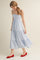 woman wearing a blue and white striped midi dress with a tiered skirt and red flats