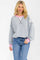 woman wearing a grey oversized sweatshirt with pink accents and long sleeves, paired with blue jeans