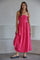 woman wearing a strapless pink maxi dress with a ruched bodice and flowy skirt, standing on a gray background