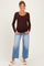 woman wearing a brown long sleeve maternity top and light blue wide-leg jeans with a visible baby bump