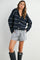 woman wearing a navy striped cropped cardigan and gray and white striped shorts with rain boots