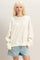 woman wearing a cream floral print oversized sweatshirt with long sleeves and distressed denim shorts