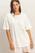 woman wearing a white oversized t-shirt with a chest pocket and smiling at the camera