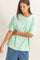 woman wearing a mint green oversized t-shirt with a pocket and short sleeves, paired with blue shorts