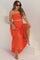 woman wearing a red strapless maternity top and matching maxi skirt, sitting on stairs with a baby bump visible
