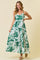 woman wearing a green and white floral maxi dress with a tiered skirt and adjustable spaghetti straps