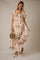 woman wearing a floral maxi dress with a square neckline and short ruffled sleeves, holding a woven bag