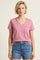 woman wearing a pink v-neck t-shirt with a pocket and high-waisted denim shorts