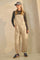 woman wearing beige striped overalls with a gray long sleeve top and a baseball cap, paired with navy sneakers