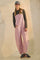 woman wearing pink and white striped overalls with a dark long sleeve top and a gray cap, styled with casual sneakers