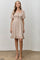woman wearing a beige puff sleeve smocked dress with a square neckline and ruffle hem