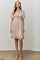 woman wearing a beige puff sleeve smocked dress with a square neckline and ruffle hem