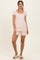 woman wearing a white short sleeve pajama set with orange floral print and matching shorts, standing with a relaxed pose