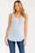 woman wearing a white floral print tank top with a scoop neckline and blue jeans