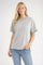 woman wearing a gray short sleeve t-shirt with teal trim and blue high-waisted jeans