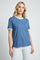woman wearing a blue short sleeve t-shirt with mint green trim and white jeans