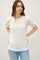 woman wearing a white short sleeve top with puffed sleeves and styled with light blue jeans