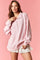 woman wearing a light pink oversized pullover sweatshirt with a half zipper and ruffled white shorts