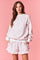 woman wearing a white sweatshirt with pink floral pattern and matching shorts with ruffle hem