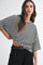 woman wearing a black and white striped oversized t-shirt with wide sleeves and high-waisted black trousers