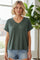 woman wearing a dark green short sleeve v-neck top paired with light denim shorts in a bright indoor setting