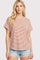 woman wearing a coral and white striped short sleeve top with rolled sleeves and distressed denim shorts