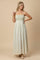 woman wearing a cream maxi dress with green geometric patterns and thin spaghetti straps