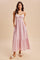 woman wearing a light pink maxi dress with adjustable straps, lace detailing, and pockets