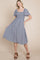 woman wearing a blue and white striped square neck dress with short flutter sleeves and a smocked bodice