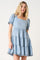 woman wearing a light blue tiered denim dress with short puff sleeves and square neckline