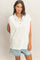 woman wearing a white sleeveless polo top with button detailing and denim shorts