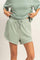 woman wearing a light green oversized sweatshirt and matching drawstring shorts