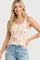 woman wearing a floral patterned tank top with pink trim and light blue distressed denim shorts