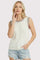 woman wearing a white sleeveless crochet sweater with colorful trim and denim shorts