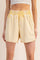 woman wearing yellow distressed high-waisted shorts with an elastic waistband and side pockets