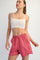 woman wearing a white crop top and pink sweat shorts with an elastic waistband