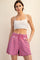 woman wearing a white cropped tank top and pink denim shorts with an elastic waistband and pockets