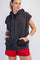 woman wearing a dark gray sleeveless hoodie with a front pocket and red athletic shorts