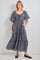 woman wearing a black and white checked maxi dress with puff sleeves and pockets