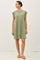 woman wearing a relaxed fit olive green cap sleeve dress with a round neckline and side pockets