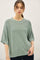 woman wearing a loose-fitting, light green short-sleeve sweater with a round neckline and ribbed detailing