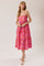 woman wearing a pink floral midi dress with spaghetti straps and a tiered skirt